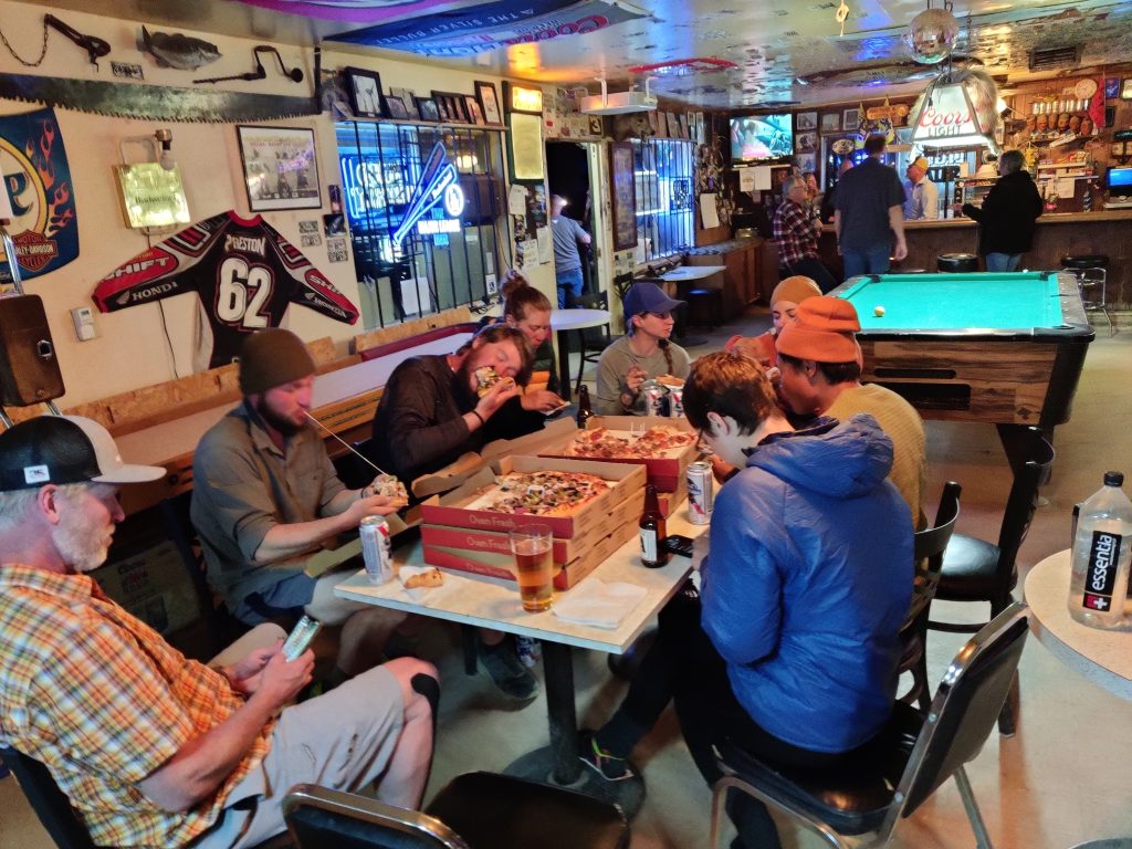 A few hungry hikers eating many pizzas.