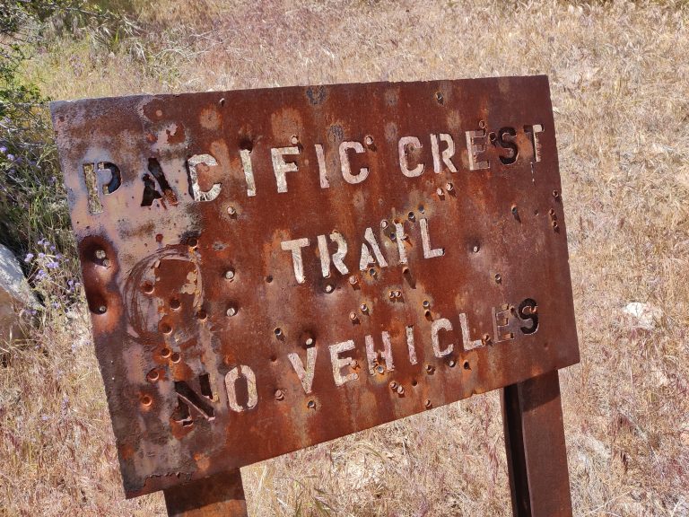 Rusty sign with holes shot through