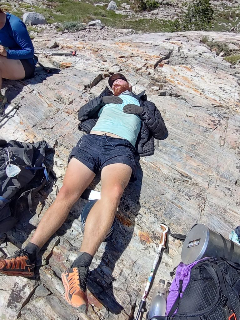 Hiker napping on a sun‑warmed rock. tired but content